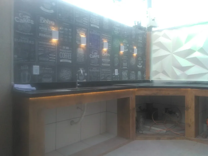 Área gourmet em obra com bancada e revestimento decorativo