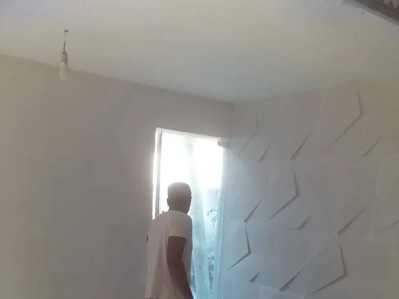 Profissional aplicando acabamento em parede com revestimento geométrico